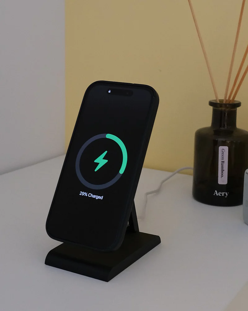 iPhone charging on the HPER, on a white cabinet next to a diffuser